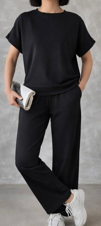 Person wearing a black outfit with white sneakers against a gray background