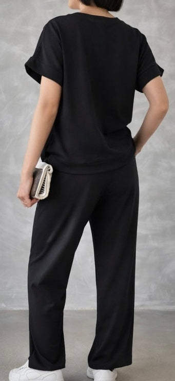 Person wearing a black outfit with white shoes against a gray background