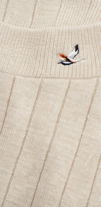Close-up of a beige knitted fabric with a small embroidered design.