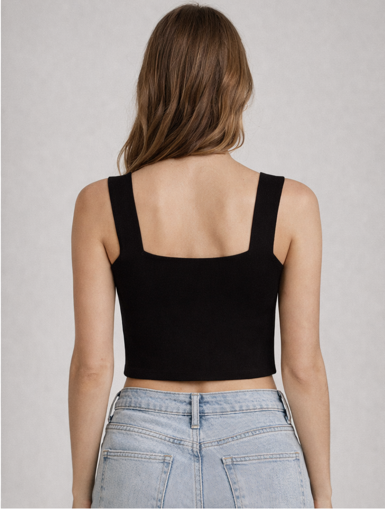 Person wearing a black tank top and light blue jeans on a plain background