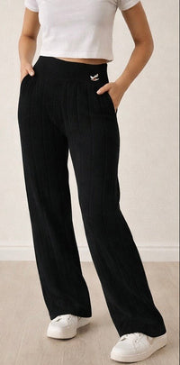 Person wearing black wide-leg pants and white shoes on a light wooden floor.