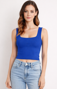 Woman wearing a blue tank top and light blue jeans against a plain background