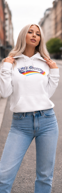 Two images of a person wearing a white hoodie with a rainbow design and text, standing outdoors.