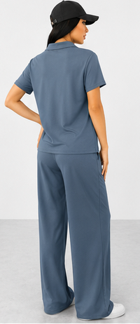 Woman wearing a blue outfit with wide-leg pants and a black cap on a white background