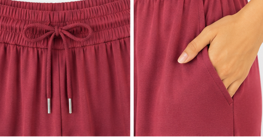 Maroon trouser close up with drawstring and pocket detail on a white background