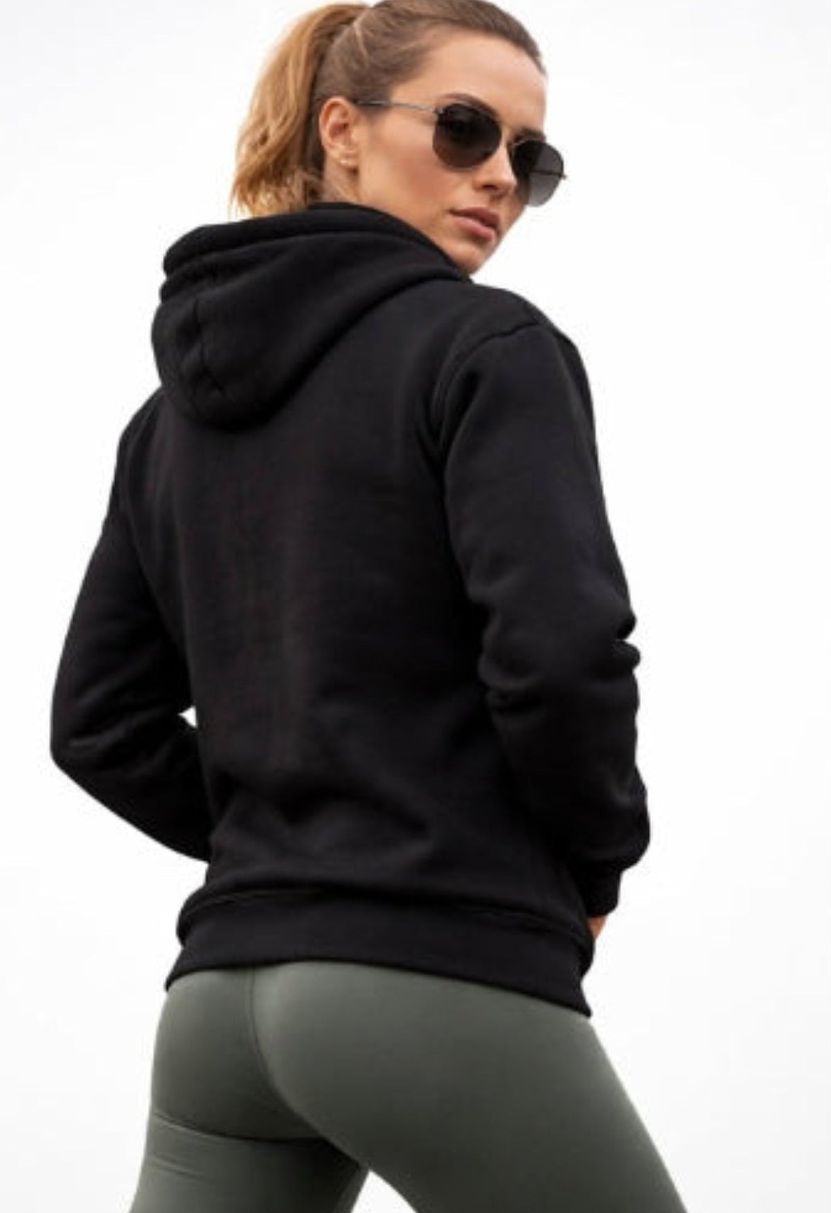 Person wearing a black hoodie and gray leggings on a white background
