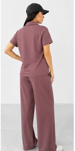 Person wearing a mauve outfit with wide-leg pants and a matching top on a white background