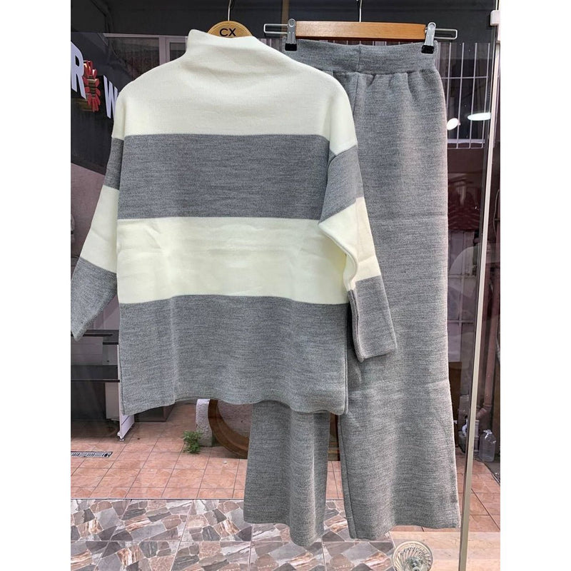 Gray and white striped sweater and pants set on a hanger against a store interior background.
