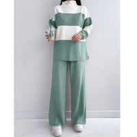 Person wearing a green and white striped outfit with wide-leg pants, holding a Starbucks cup.