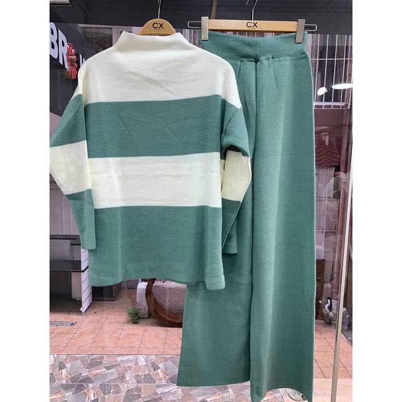Green and white striped sweater and pants on hangers with a store interior background.