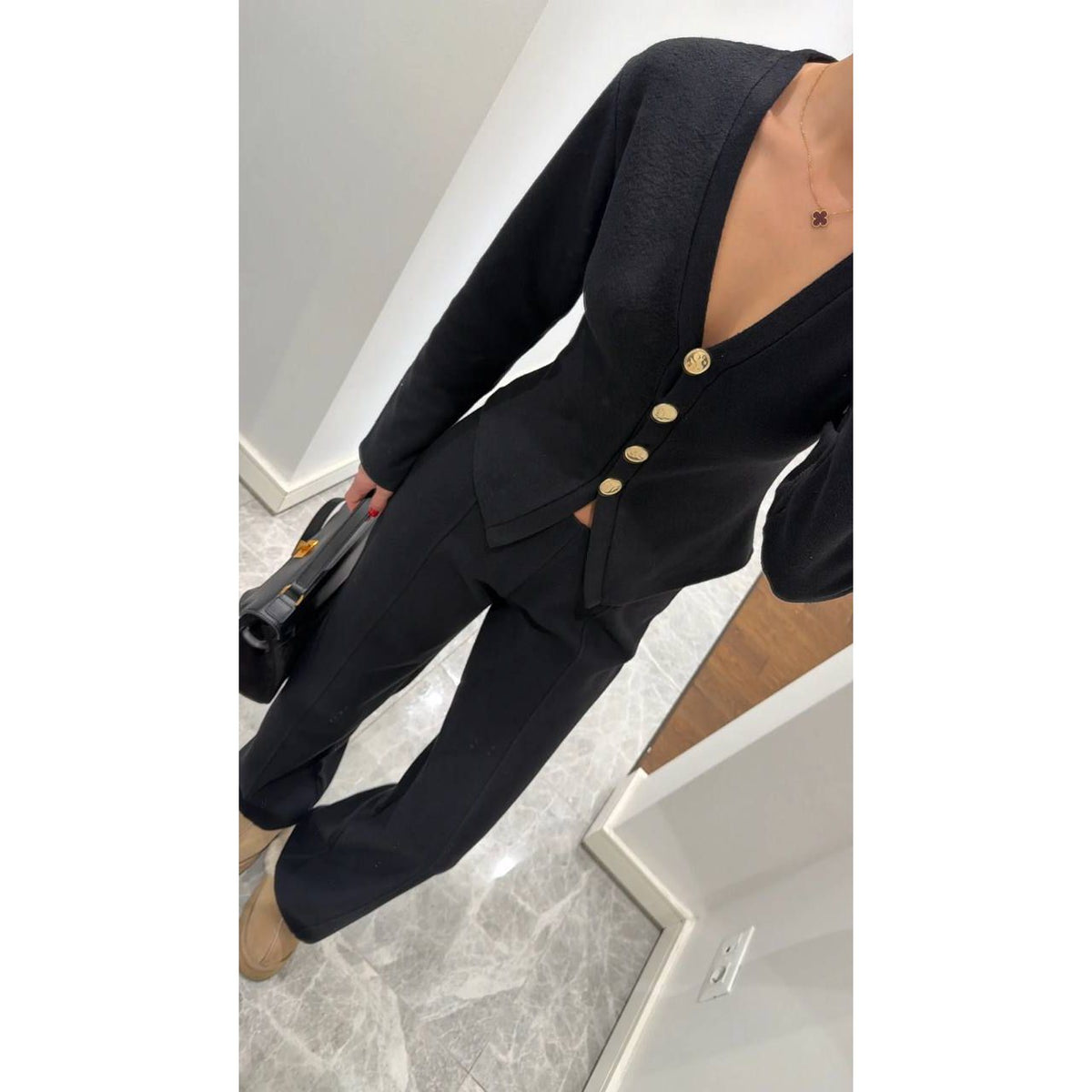 Person wearing a black suit with gold buttons in an indoor setting