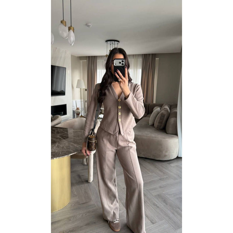 Person taking a mirror selfie in a stylish beige suit in a modern living room.