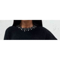 Black sweater with a beaded neckline against a light background