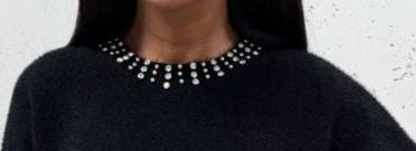Black sweater with a beaded neckline against a light background