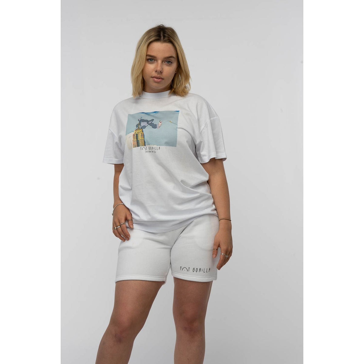 Woman wearing a white t-shirt with a graphic design and matching shorts on a plain background