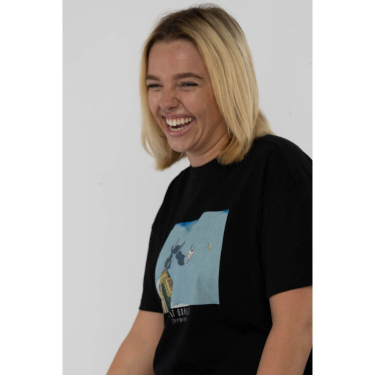 Person wearing a black t-shirt with a graphic design on a plain background