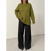 Person wearing a green sweater and black pants against a white background