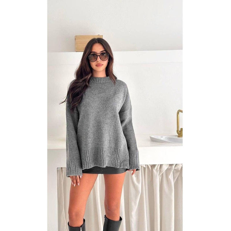 Woman wearing a gray sweater and black boots in a minimalistic setting