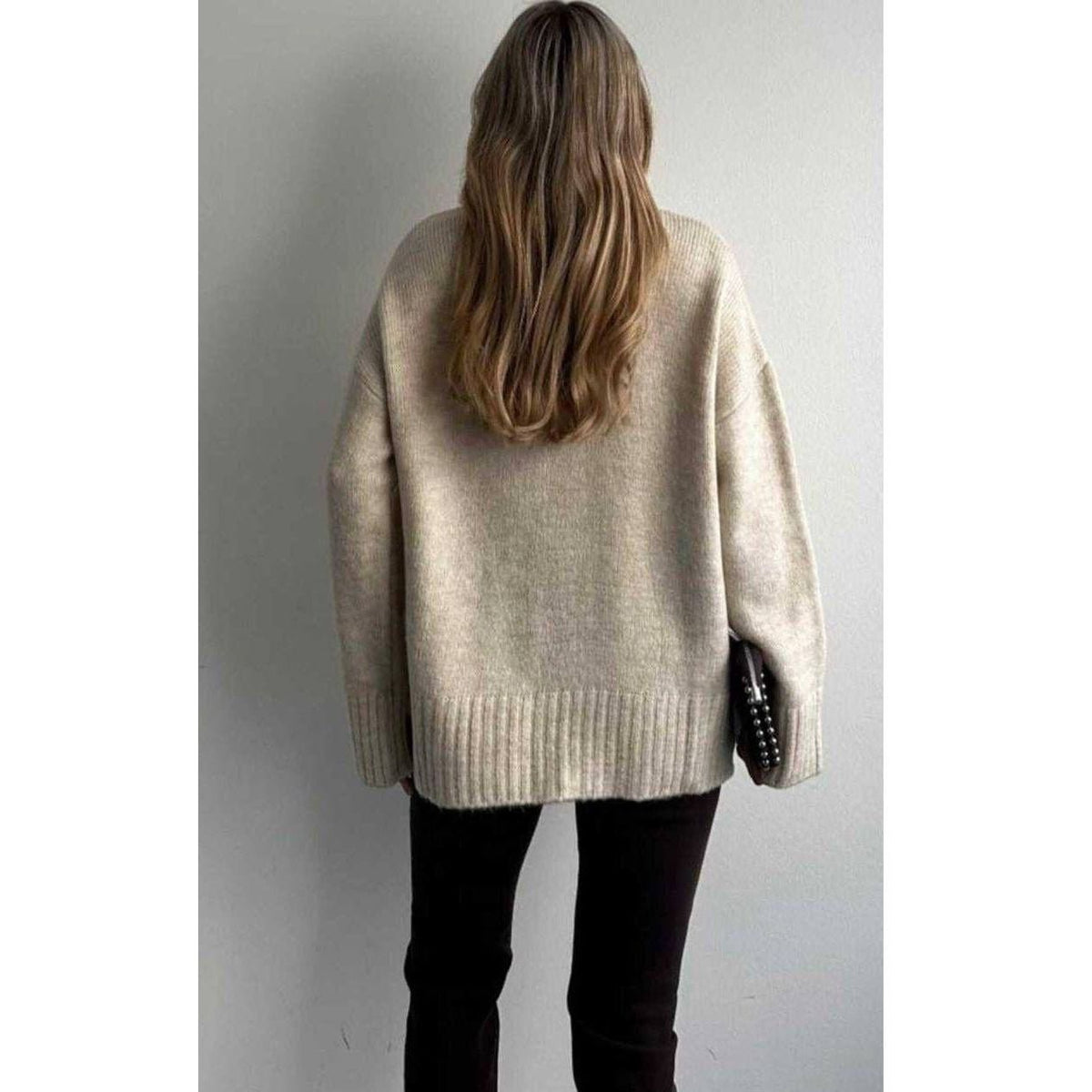 Person wearing a beige sweater against a plain background