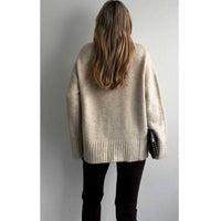 Person wearing a beige sweater against a plain background