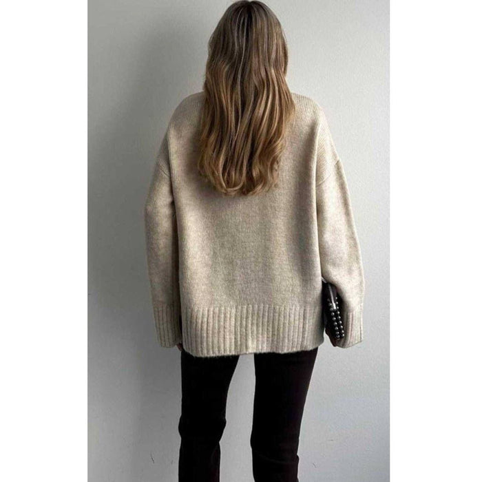 Person wearing a beige sweater against a plain background