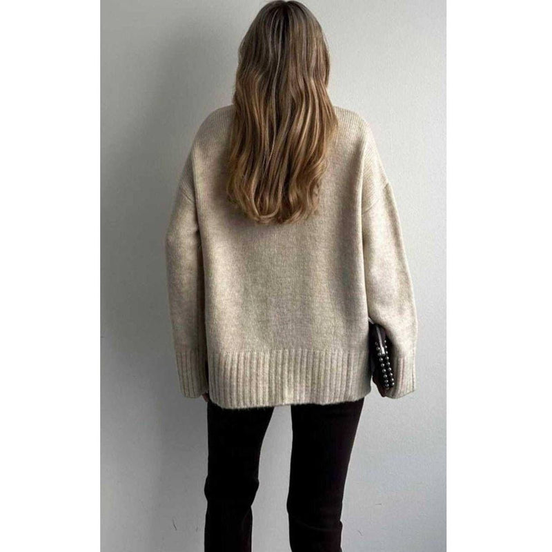 Person wearing a beige sweater against a plain background