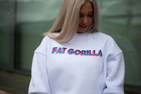 Person wearing a white sweatshirt with 'FAT GORILLA' text, standing against a green wall.