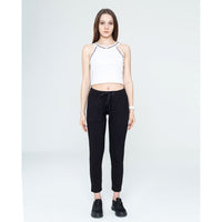 Woman wearing a white crop top and black pants on a white background