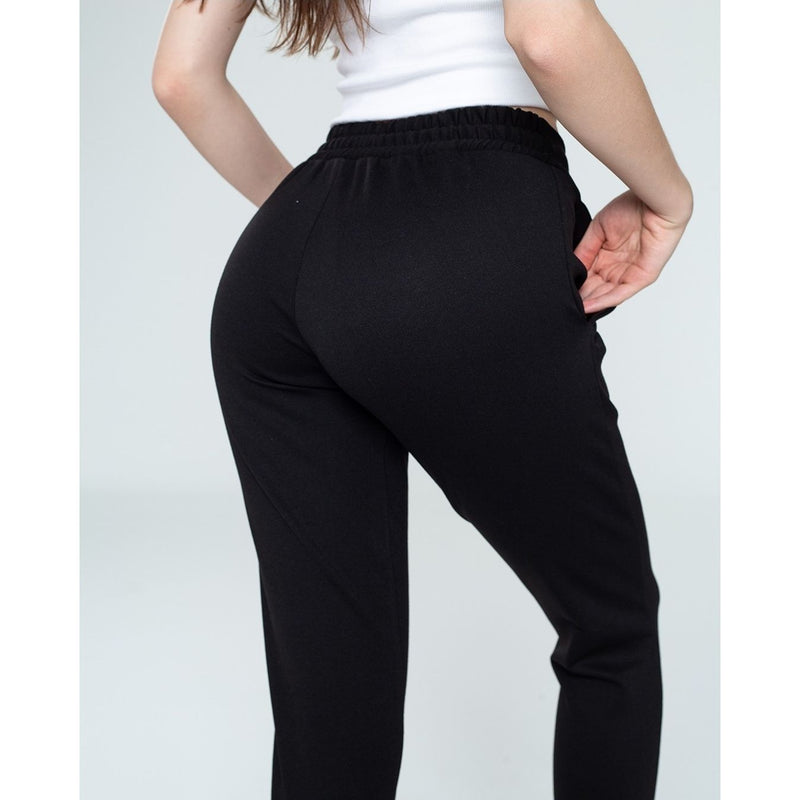 Person wearing black pants on a plain background
