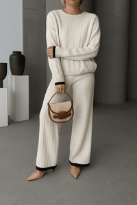 Person wearing a white outfit holding a woven handbag in a minimalistic setting