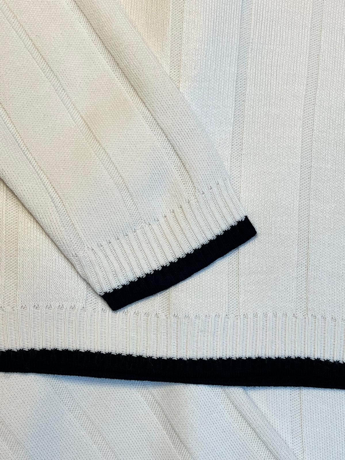 Close-up of a white sweater with black trim on a light gray background